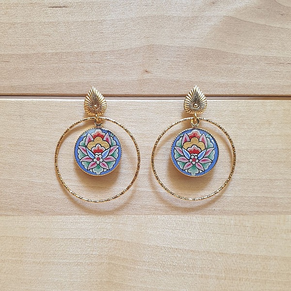 Boucles d'oreilles pendantes fleur orientale sur anneaux dorés.