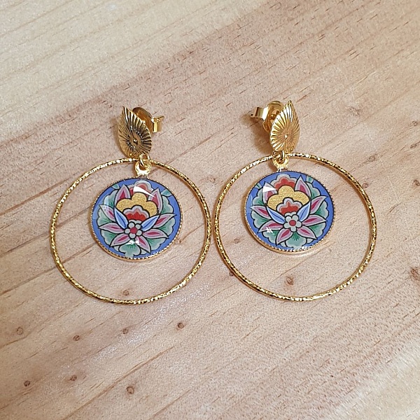 Boucles d'oreilles pendantes dorées avec fleur orientale bleue.