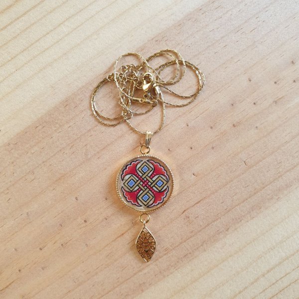 Halsk&aelig;de vedh&aelig;ng belyst med bl&aring; palmetter, guld og r&oslash;de fletninger p&aring; guldk&aelig;de