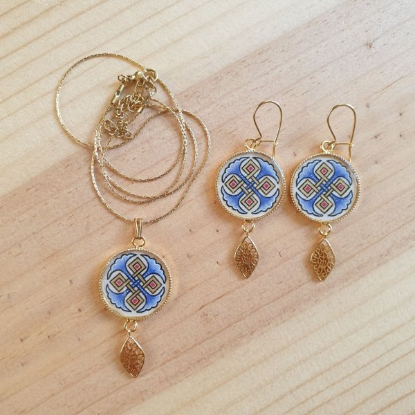 Halsk&aelig;de vedh&aelig;ng belyst med bl&aring; palmetter, guld og r&oslash;de fletninger p&aring; guldk&aelig;de