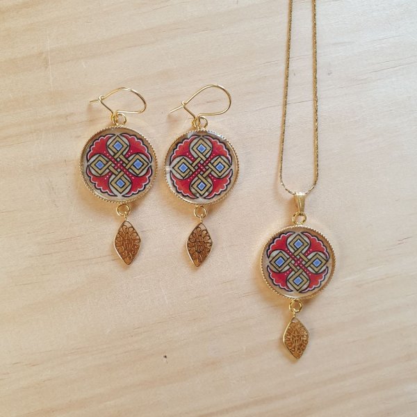 Halsk&aelig;de vedh&aelig;ng belyst med bl&aring; palmetter, guld og r&oslash;de fletninger p&aring; guldk&aelig;de