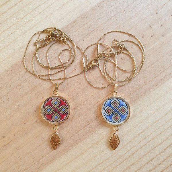 Halsk&aelig;de vedh&aelig;ng belyst med bl&aring; palmetter, guld og r&oslash;de fletninger p&aring; guldk&aelig;de